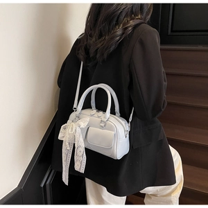 Detail view of stylish light blue pillow bag with white lace bow and pearl pendant charm