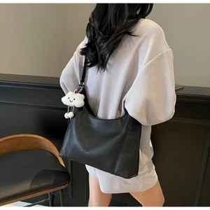 Detail of black pebbled leather tote bag with cloud charm and small logo