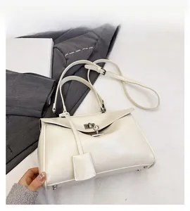 Detail view of cream white patent leather handbag with silver metallic turn-lock closure