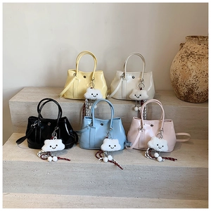 Detail of colorful mini patent leather handbags with cute cloud charms on stone steps