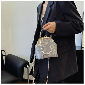 Detail of floral brocade bag with pearl handle and golden chain strap on a model
