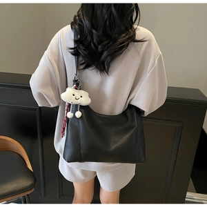 Close-up of black lychee grain hobo bag with a cute white fluffy cloud pendant accessory