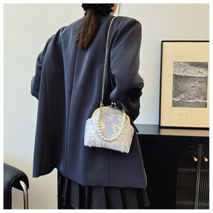 Detail of lavender floral embroidery bag with pearl handle worn with a grey blazer