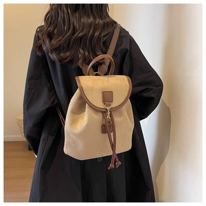 Détail du sac à dos en daim kaki avec finitions cuir et boucle dorée porté par un mannequin