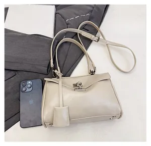 Detailed view of off-white crossbody bag with metal rotary lock next to a smartphone