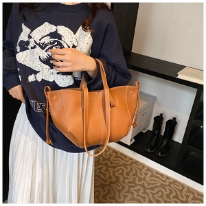 Détail du sac seau en cuir marron avec surpiqûres blanches et texture grainée de litchi