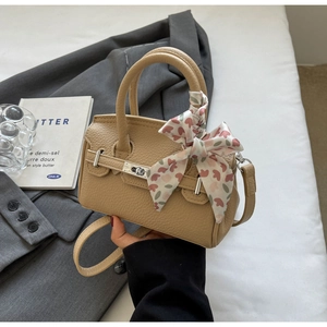 Detail einer hellbraunen Lederhandtasche mit Seidenschal mit Herzmuster am Griff
