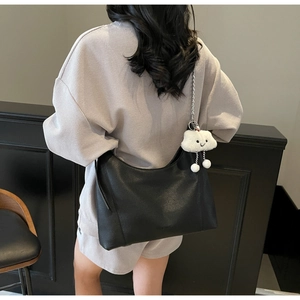 Detail of black pebbled leather hobo bag with silver chain strap and white plush cloud charm