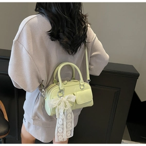 Close-up of mint green Boston bag with pearl bow charm and adjustable shoulder strap