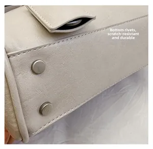 Detail shot of silver metal rivets on the bottom of a textured beige leather handbag