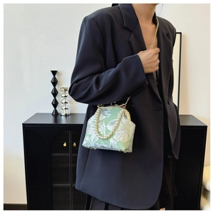 Detail of embroidered floral handbag with pearl handle and gold chain on a model