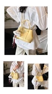 Close-up of a light yellow faux leather handbag with silver buckle and cloud charm