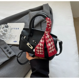 Nahaufnahme der schwarzen Mini-Handtasche aus genarbtem Leder mit Seidenschal am Griff