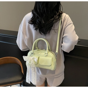 Close-up of mint green patent leather mini bag with lace bow and pearl charm detail