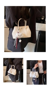 Detail of glossy beige handbag with plush cloud charm and metal chain strap