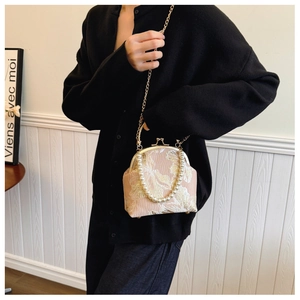 Detail of pink embroidered evening bag with pearl handle and gold floral stitching