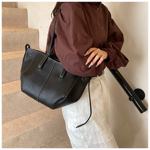 Détail d'un sac cabas en cuir à motif litchi avec surpiqûres contrastées et rivets latéraux