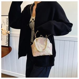 Model wearing a pink floral embroidery bag with large pearl handle and gold chain