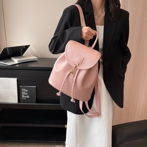 Pink PU leather backpack with flap and drawstring closure shown in a modern home office