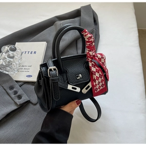 Detail der schwarzen Kieselleder-Handtasche mit rot-kariertem Seidenschal-Griff und Silber-Verschluss