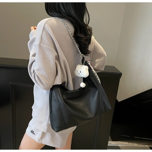 Detail view of black pebble leather hobo bag with silver chain and white plush cloud charm