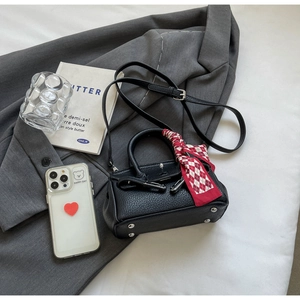 Detailansicht der schwarzen Mini-Handtasche aus Leder mit dekorativem Seidenschal-Griff