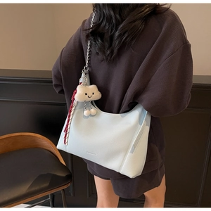 Detail of light blue pebble leather tote with silver chain and plush cloud charm