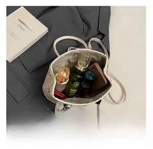 Detail showing internal capacity of the cream bucket bag with phone and cosmetics