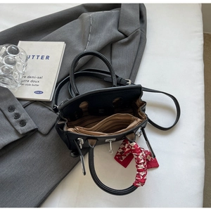 Detail der schwarzen Lederhandtasche mit gestreiftem Futter, Reißverschluss und Seidenschal
