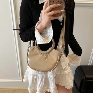 Sac à main demi-lune beige chic avec poignée ronde et bandoulière sur une tenue