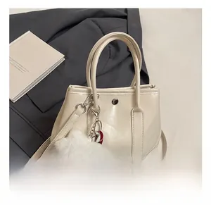 Detail showing cream leather handbag with silver hardware and plush bear charm decoration