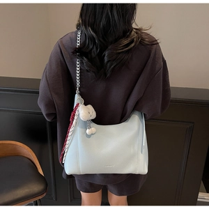 Detail of light blue hobo bag with silver chain strap and plush keychain on model