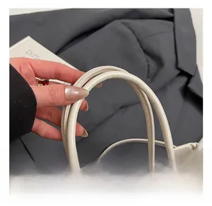 Detail view of thickened round handles and metallic hardware on cream bucket bag