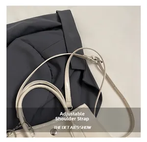 Detail of adjustable shoulder strap and silver metal buckle on a beige leather handbag