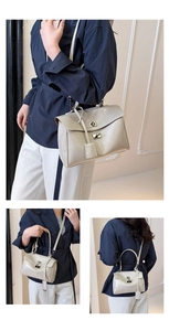 Detail view of cream textured leather tote bag with metallic twist lock and slim strap