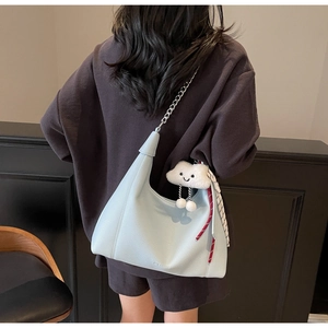 Close-up of light blue lychee pattern leather tote bag with silver chain and plush pendant