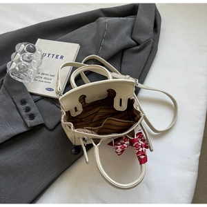 Detail der beigen Leder-Minitasche mit gestreiftem Futter und Seidenschal-Dekor am Griff
