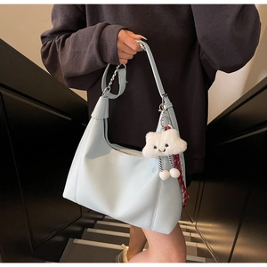 Close-up of light blue litchi pattern hobo bag with silver chain and white plush charm