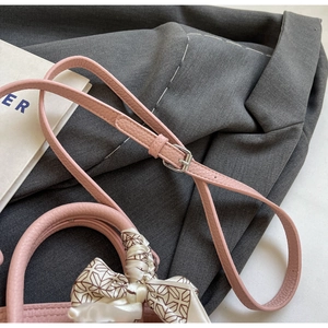 Detail der Handtasche aus pinkfarbenem Lychee-Leder mit Seidentuch und Gurt