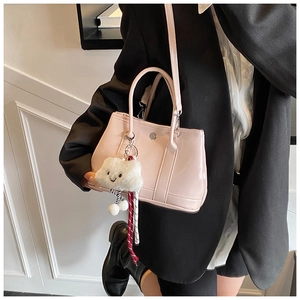 Detail of pink patent leather handbag with cloud plush charm and metallic clasp