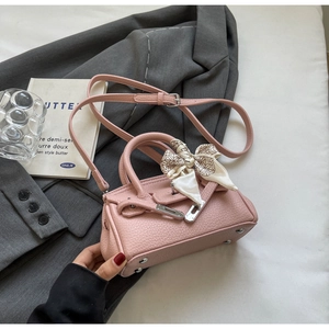 Detail der rosa Handtasche aus Narbenleder mit dekorativem Seidentuch und Silberteilen