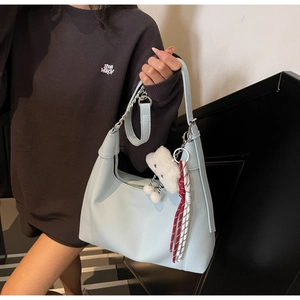 Close-up of light blue lychee leather hobo bag with silver chain and plush cloud charm