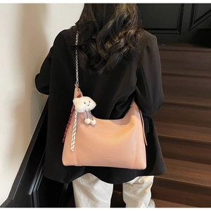 Close-up of pink litchi grain leather tote with silver chain and cloud plush charm