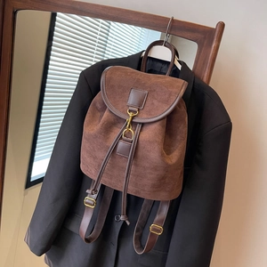 Minimalist brown suede backpack with vintage gold hook on a black blazer