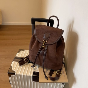 Brown frosted leather mini backpack with vintage buckle on a white suitcase
