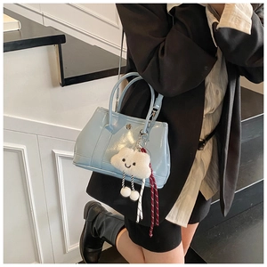 Close-up of light blue glossy bucket bag with white cloud charm on a shoulder strap