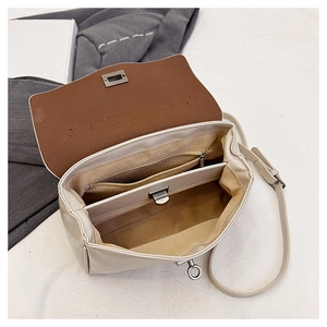 Detailed interior of a cream shoulder bag showing multiple compartments and metal zippers