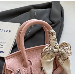 Nahaufnahme der rosa Handtasche aus Leder mit Seidenschal und silbernem Metallverschluss