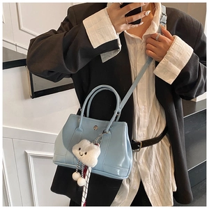Detail of light blue patent leather bag with a white plush cloud charm on the handle