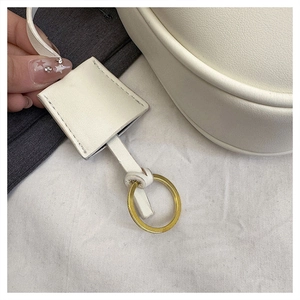 Close-up of white lychee leather handbag detail with gold ring and matching tag ornament
